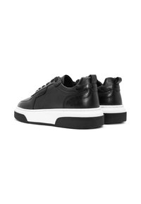 Zwarte leren sneakers met een gestructureerd oppervlak, rond neus, witte tussenzool en zwarte rubberen outsole; uitgerust met vetersluiting en achtertab.