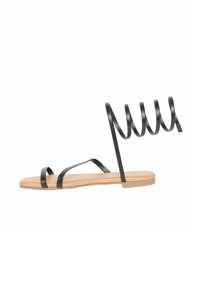 Sandali neri piatti con sottili spirali alla caviglia, design open-toe e suola di colore naturale. Le cinghie sono realizzate in un materiale liscio e opaco.