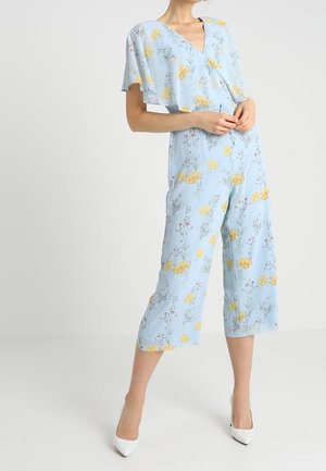Jasnoniebieski kombinezon w kwiaty z krótkimi rękawami, dekoltem w kształcie litery V i żółtymi wzorami kwiatowymi, z szerokimi nogawkami w długości 3/4.