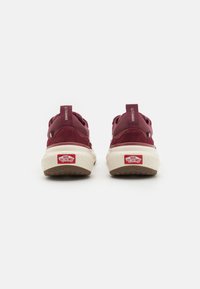 Burgundske Vans tenisice s gornjim dijelom od nubucka i tekstila, bijelim teksturiranim srednjim dijelom i kontrastnim crvenim logom na peti.
