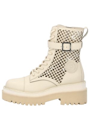Beiger Schnür-Stiefelette mit dicker Gummisohle, seitlichen Netzgewebeeinsätzen, verstellbarem Schnallenriemen und gebrandetem rundem Patch an der Außenseite.