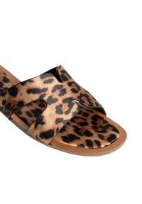Chanclas deslizantes de estampado de leopardo con amplias correas cruzadas, hechas de tela suave, con una suela plana y diseño abierto para un fácil uso.
