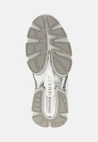 Semelle en argent avec des motifs texturés variés, présentant un design strié et un logo "GUESS" en évidence au centre.