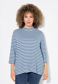 Randig topp i ljusblått med svarta horisontella ränder, rund halsringning och trekvartsärmar. Mjuk tygkvalitet med avslappnad passform.