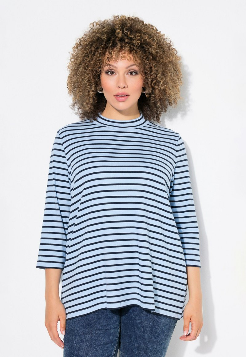Randig topp i ljusblått med svarta horisontella ränder, rund halsringning och trekvartsärmar. Mjuk tygkvalitet med avslappnad passform.
