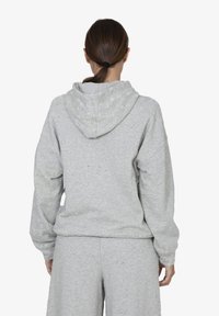 Felpa grigia con cappuccio, vestibilità rilassata e spalle scese. Realizzata in tessuto testurizzato con piccole imperfezioni e polsini elasticizzati.
