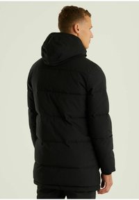 Schwarze Steppjacke mit Kapuze, gestepptem Design und mittellanger Schnittführung, mattem Finish und verdeckten Taschen.