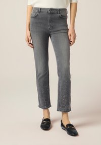 Jeans de mezclilla gris con un diseño de pierna recta, con adornos de strass en el dobladillo. Cintura alta y estilo clásico de cinco bolsillos.