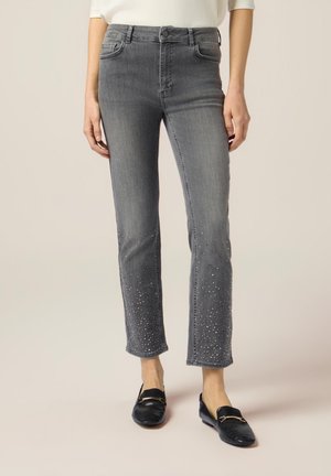 Jeans in denim grigio con un design a gamba dritta, caratterizzati da decorazioni in strass sull'orlo. Vita alta e stile classico a cinque tasche.