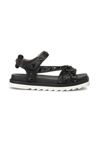 Sandalia de cuero negro con tachuelas decorativas, correas ajustables y una suela blanca gruesa con un patrón en zigzag. Diseño de punta abierta.