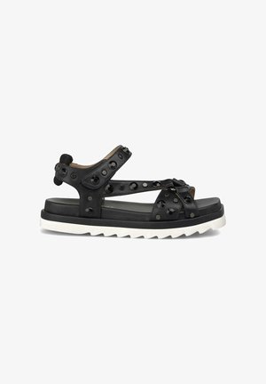 Sandale en cuir noir avec des clous décoratifs, des sangles réglables et une semelle blanche épaisse à motif en zigzag. Design à bout ouvert.