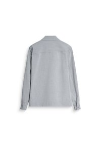 Lange mouwen shirt in lichtgrijze stof met een subtiele textuur, knoopmanchetten en een kraag. Bevat een rugpand en minimale branding.