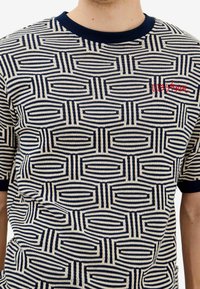 Pletená košile s krátkým rukávem s geometrickým vzorem v námořnické modři a krémové barvě, s žebrovaným námořnickým kulatým výstřihem a červeným logem.