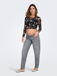 Melns ziedu raksta tops ar garām piedurknēm un caurspīdīgu audumu, apakšmala ar viļņotu malu, kopā valkāts ar gaiši pelēniem džinsiem ar taisnām kājām un bēšām dzīvokļa kurpēm.