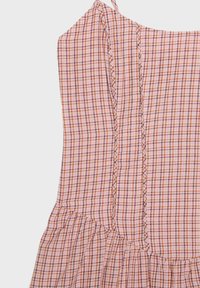 Robe sans manches à carreaux rose et orange avec une taille froncée et de délicats liens en tissu à l'épaule.