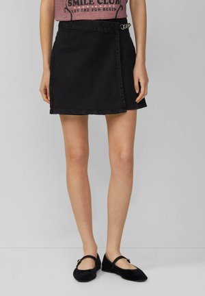 Zwarte denimrok met een wikkelontwerp, voorzien van een zilveren kettingaccent op de tailleband. Glad textuur, lengte boven de knie.
