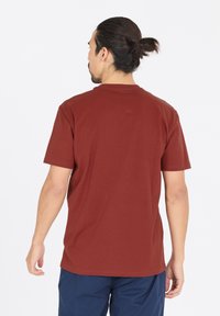 Körsbärsröd kortärmad t-shirt i bomull, med rund hals och en avslappnad passform, sedd bakifrån, med en slät textur.