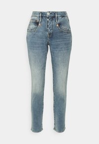 Ljusblå denimjeans med hög midja, femficksdesign och knapplåsning. Har lätt blekningar på låren och avsmalnande anklar.