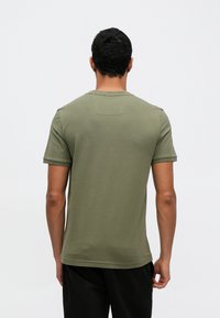 Olivovo zelené tričko s krátkym rukávom a okrúhlym výstrihom, s malou štipkou na zadnej strane. Materiál má hladkú, ľahkú textúru.