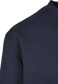 Suéter azul marino hecho de algodón suave, con un cuello redondo acanalado y una textura lisa, con una silueta ajustada y detalles de costura mínimos.