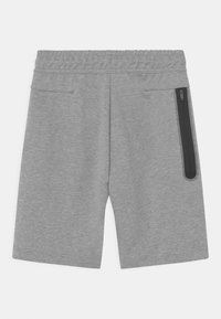 Grå atletiska shorts med en slät yta, elastisk midja och en ficka med dragkedja på sidan. Kantad ovanför knäna.