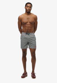 Heren zwembroek in een zwart-wit gespoten patroon met een tailleband met trekkoord. Bevat een rode logodetail aan de voorkant.