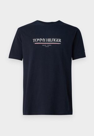 Marineblå bomulds t-shirt med et hvidt logo med røde detaljer, der står "TOMMY HILFIGER NEW YORK 1985", korte ærmer og rund hals.