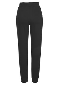 Schwarze Sweatpants mit glatter Textur, elastischem Bund und schmal zulaufenden Beinen mit gerippten Bündchen, entworfen für Komfort und Beweglichkeit.