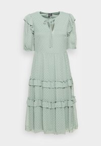 Helles grünes Midi-Kleid mit strukturierten Punkten, kurzen Puffärmeln, Rüschenstufen und einem vorn gebundenen Ausschnitt.