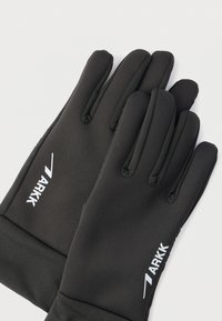 Ζευγάρι μαύρα γάντια με λευκό λογότυπο "ARKK" εκτυπωμένο στην πίσω πλευρά, τοποθετημένα επίπεδα σε ένα απλό ανοιχτόχρωμο φόντο.