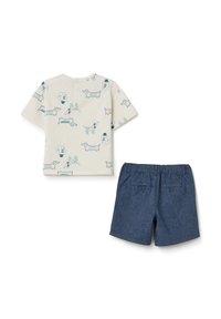 Camisa de manga corta color crema con estampados de teckel azules, combinada con pantalones cortos azul oscuro con cintura elástica y bolsillos traseros.