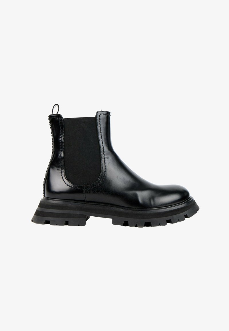Botte Chelsea en cuir noir avec panneau latéral élastique, languette au talon et semelle épaisse à crampons avec motif rayé.