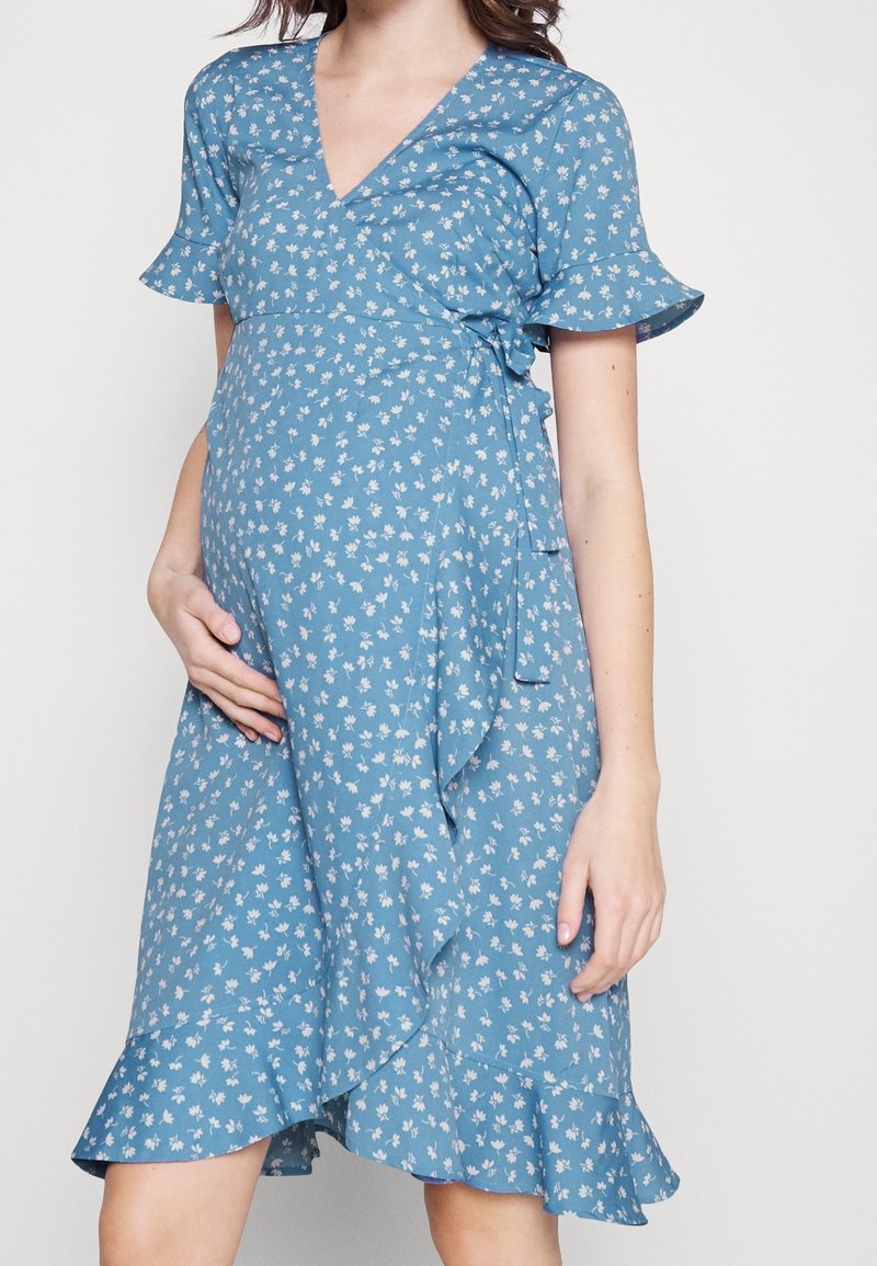 Blaues Blumen-Wickelkleid mit kurzen Rüschensäumen, V-Ausschnitt und gebundenem Taillenband, das einen fließenden Rock mit rüschengesäumtem Saum hat.
