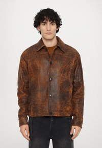 Giacca in pelle marrone con una finitura testurizzata e patterned, dotata di un colletto, chiusura a bottone e due tasche frontali.