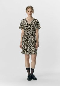 Robe imprimée léopard en beige et noir, avec un décolleté en V, des manches courtes, une ceinture à nouer à la taille et une coupe décontractée au-dessus du genou.