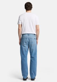 Ljust blå denimjeans med rak passform, fem fickor och en urtvättad finish, tillsammans med en enkel vit t-shirt.