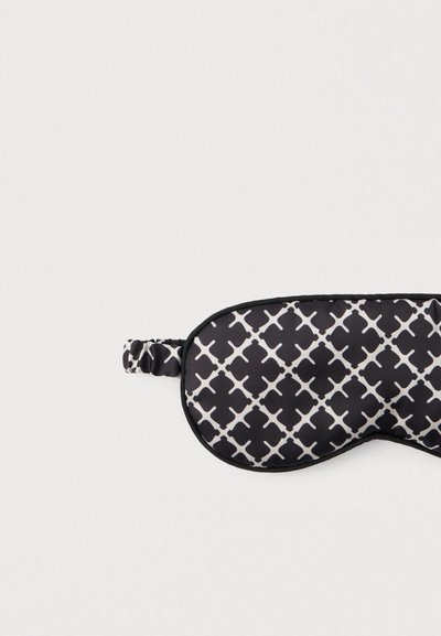 Mască de dormit alb-negru cu un model geometric, căptușită pentru confort, prevăzută cu o bandă elastică pentru o fixare sigură.