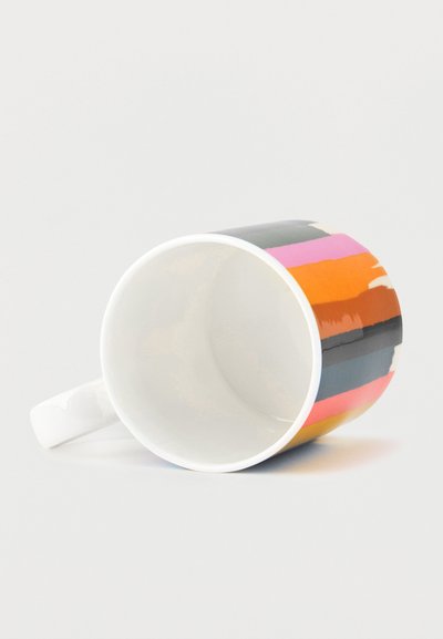 Tasse en céramique blanche posée sur le côté avec des rayures horizontales colorées en rose, orange, noir et gris autour de l'extérieur.