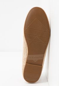 Semelle d'une chaussure tissée beige avec une semelle extérieure en caoutchouc marron, motif de grip texturé, nom de marque Tamaris et indication de la taille 37.