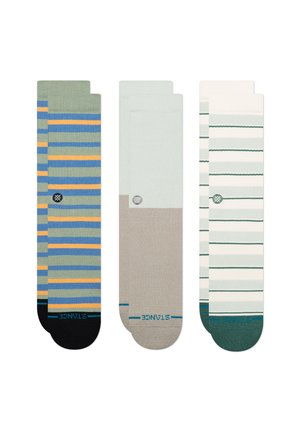 Drie paar sokken met verschillende ontwerpen: gestreept groen, blauw en oranje; een effen beige; en gestreept wit met groene accenten.