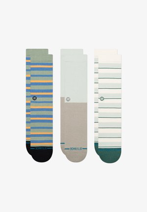 Drie paar sokken met verschillende ontwerpen: gestreept groen, blauw en oranje; een effen beige; en gestreept wit met groene accenten.