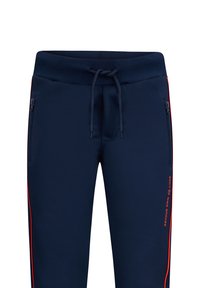 Marineblaue Jogginghosen mit Kordelzugbund, seitlichen Reißverschlusstaschen und roten Seitenstreifen. Glatte Stoffoberfläche mit bedrucktem Logo-Detail.