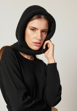Cagoule noire tricotée avec une finition texturée, conçue pour s'ajuster parfaitement autour du cou et de la tête. Tissu lisse avec des bords côtelés.