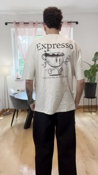 Krémové oversized tričko s grafikou rozprávkového hrnčeka kávy a textom "Expresso" na zadnej strane. Čierne nohavice.