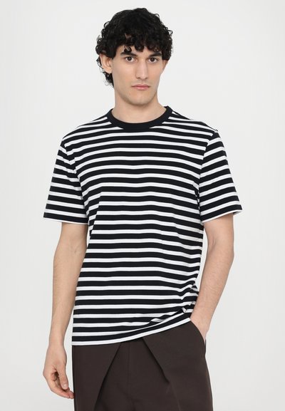 Camiseta de rayas blancas y negras con cuello redondo, mangas cortas y un ajuste holgado. El material parece suave con una textura lisa.