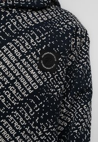 Felpa con cappuccio in tessuto blu navy con un motivo testuale bianco ripetuto. Include un'etichetta logata nera rettangolare sul petto.
