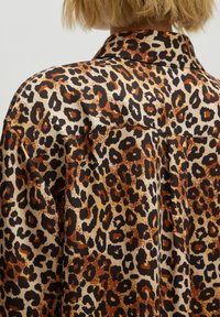 Leopardprint shirt met een soepele textuur, kraag en een mengeling van beige, bruin en zwart, met zichtbare stiksels.