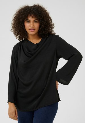 Black long-sleeve top with draped neckline and textured fabric. Features slightly flared sleeves and a relaxed fit, paired with blue jeans.