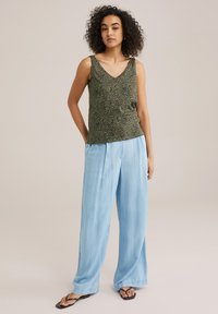 Green leopard-print sleeveless top paired with light blue wide-leg pants. The top has a v-neck design, while the pants have a soft texture.