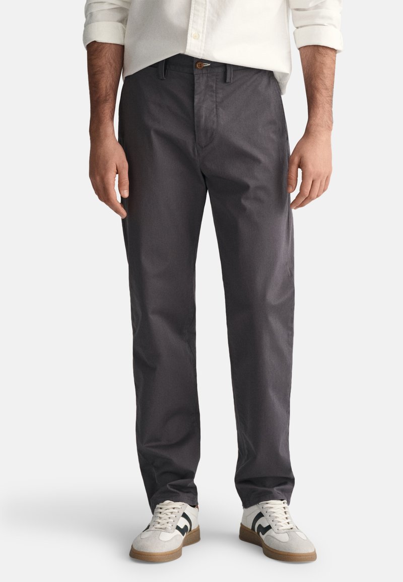 Gray, straight-leg pants with a textured finish, featuring a front button closure, side pockets, and a relaxed fit, paired with white sneakers.